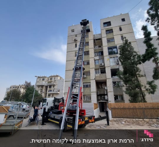 מנוף על משאית ליד בניין מגורים